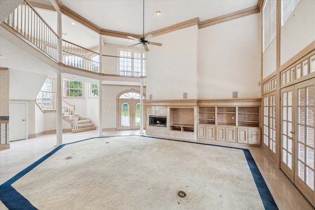 unfurnished living room with crown molding, ceiling fan, and a high ceiling