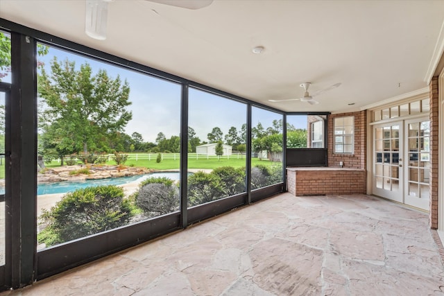 unfurnished sunroom with ceiling fan and french doors