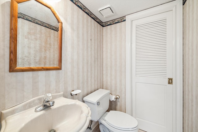 bathroom with sink, a textured ceiling, and toilet