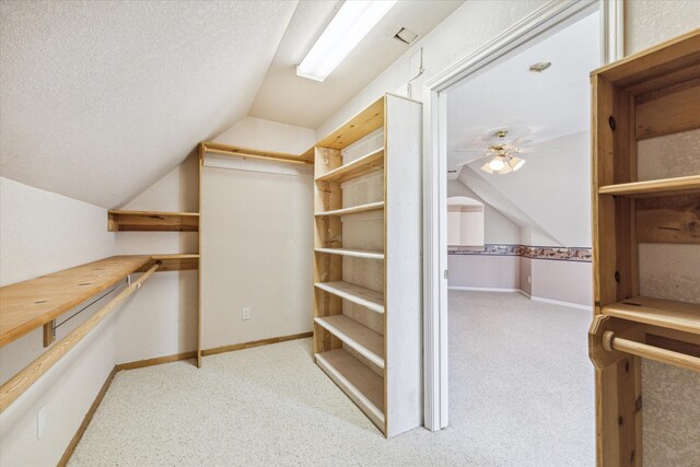 spacious closet featuring light colored carpet, vaulted ceiling, and ceiling fan