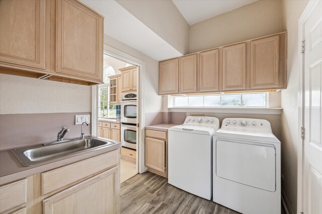 laundry area featuring cabinets, independent washer and dryer, light wood-type flooring, and sink