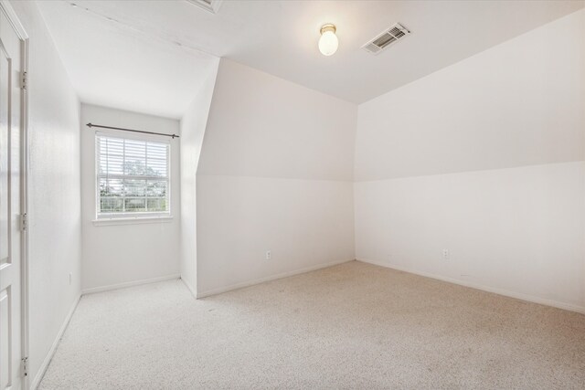 bonus room with light colored carpet and vaulted ceiling