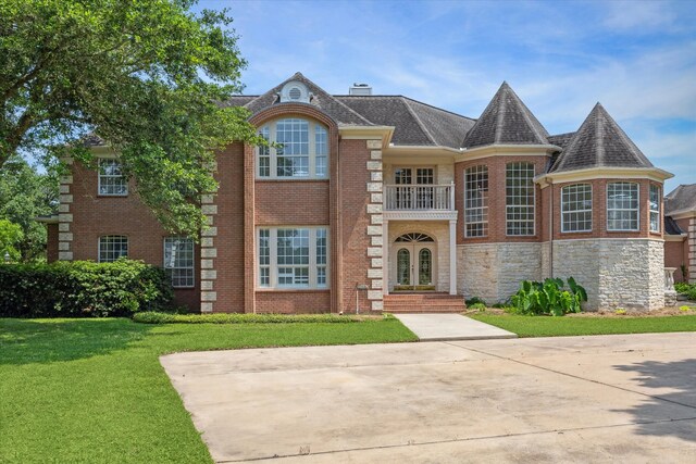 view of front of property with a front lawn, french doors, and a balcony