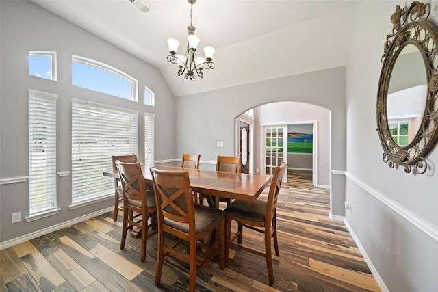 dining space featuring vaulted ceiling, hardwood / wood-style floors, and an inviting chandelier