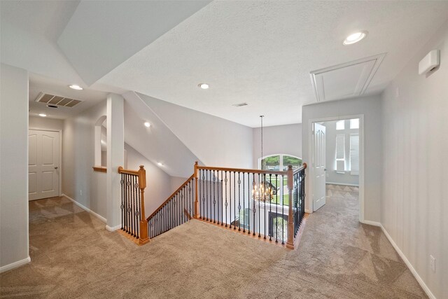 corridor featuring a textured ceiling and light carpet