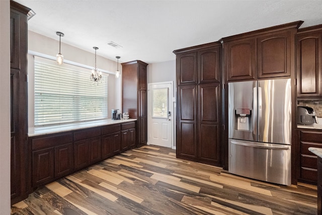 kitchen with a chandelier, stainless steel refrigerator with ice dispenser, hanging light fixtures, hardwood / wood-style flooring, and dark brown cabinets