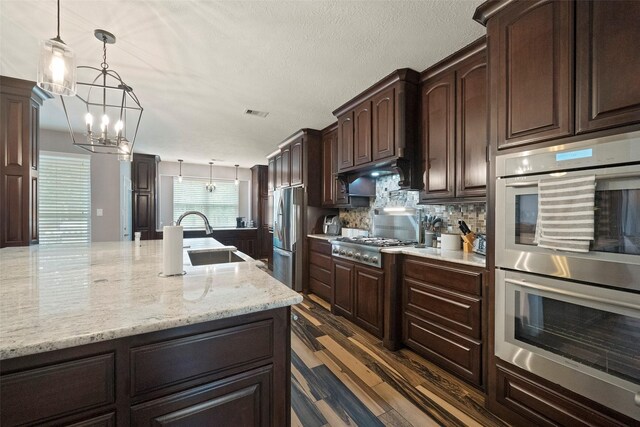 kitchen featuring stainless steel appliances, tasteful backsplash, sink, dark wood-type flooring, and hanging light fixtures