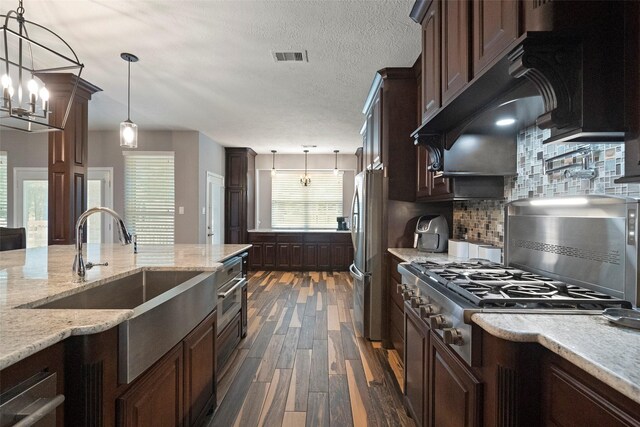 kitchen featuring decorative backsplash, light stone countertops, pendant lighting, dark hardwood / wood-style flooring, and stainless steel fridge