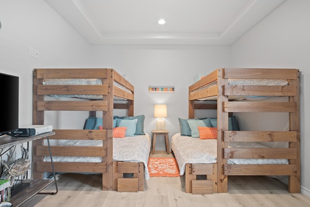 bedroom with light wood-type flooring and a tray ceiling