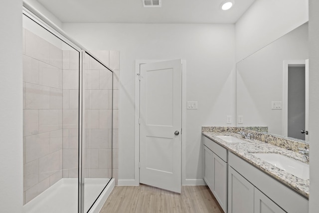 bathroom with hardwood / wood-style floors, vanity, and a shower with shower door