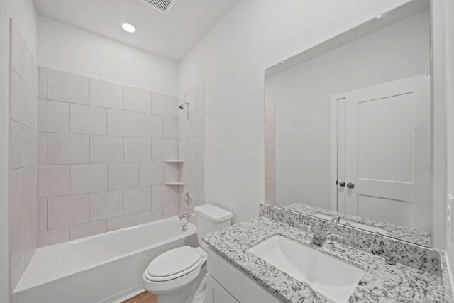 full bathroom featuring vanity, hardwood / wood-style floors, tiled shower / bath combo, and toilet