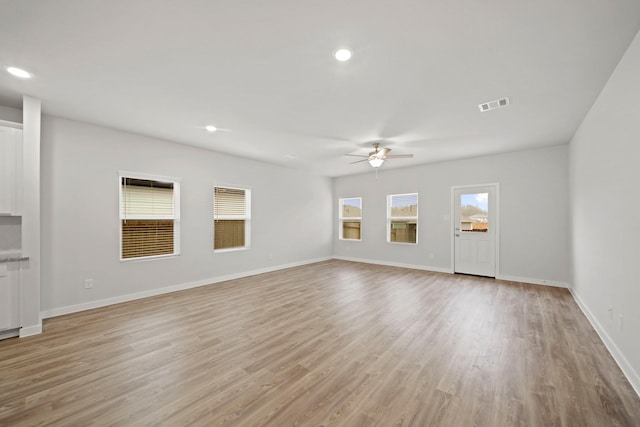 unfurnished living room featuring plenty of natural light, ceiling fan, and light hardwood / wood-style flooring