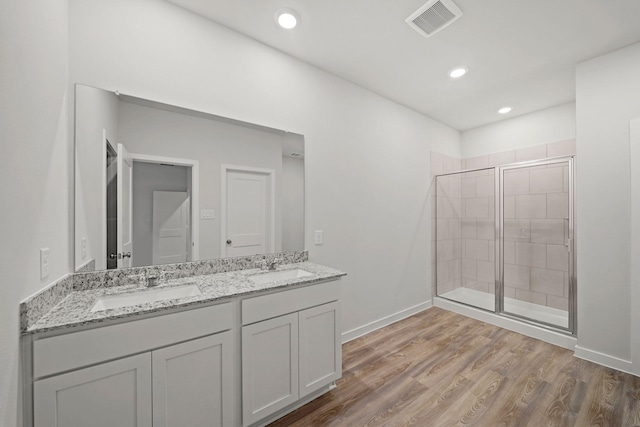 bathroom with wood-type flooring, vanity, and an enclosed shower