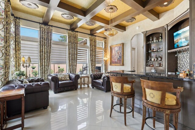 bar with light tile patterned floors, hanging light fixtures, beamed ceiling, dark stone counters, and coffered ceiling