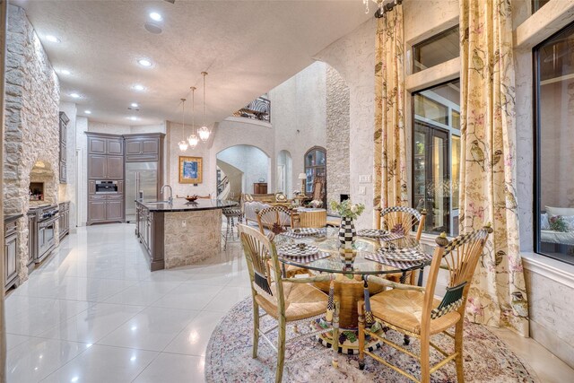 dining space with sink, a textured ceiling, and light tile patterned floors