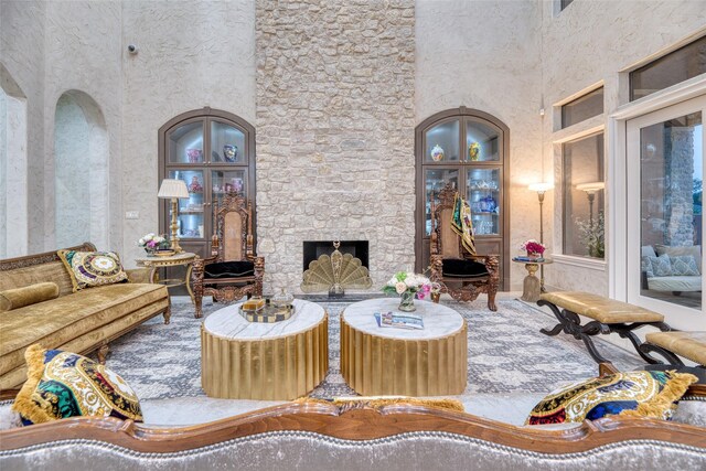 living room with a stone fireplace and a high ceiling