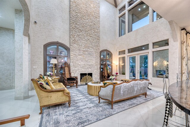 tiled living room featuring french doors, a high ceiling, and a fireplace