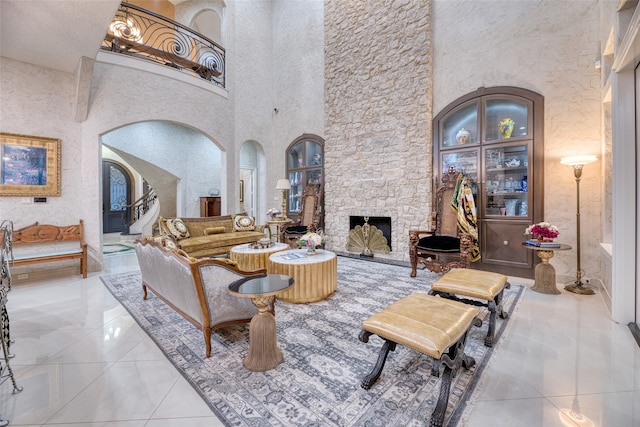 tiled living room featuring a fireplace and a high ceiling