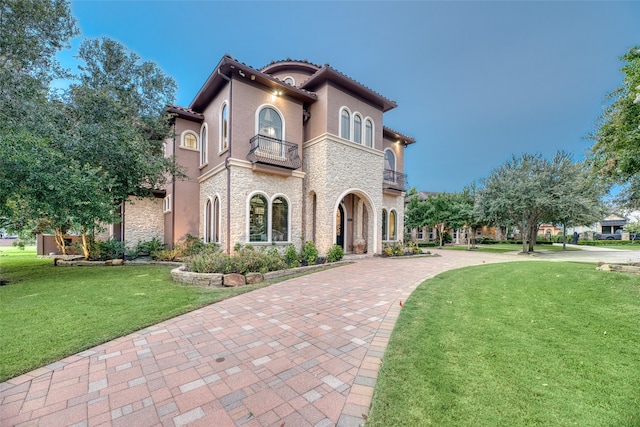 mediterranean / spanish-style home with a front yard and a balcony