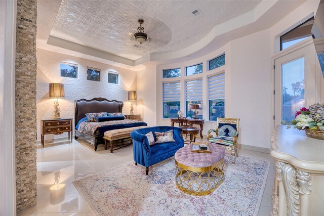 bedroom with a textured ceiling, a tray ceiling, tile patterned flooring, and ceiling fan