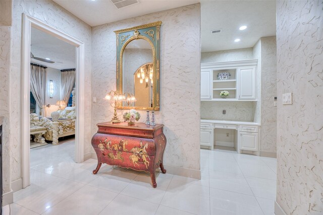 hall with light tile patterned floors and an inviting chandelier