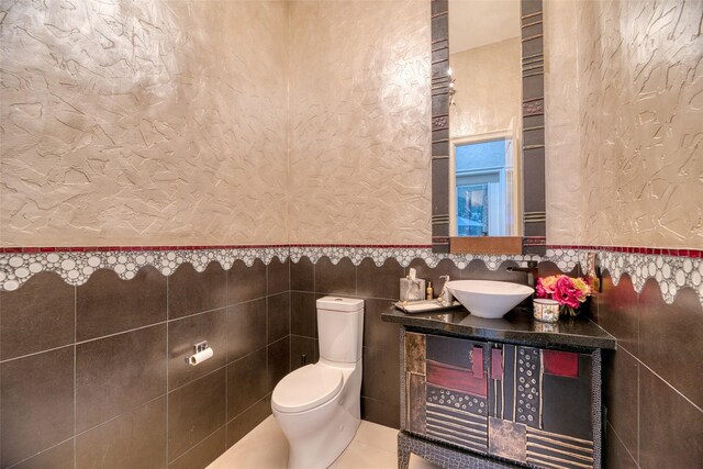 bathroom featuring tile walls, vanity, tile patterned flooring, and toilet