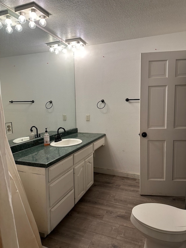 bathroom featuring hardwood / wood-style flooring, vanity, toilet, and a textured ceiling