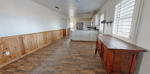 kitchen with white cabinetry, wood walls, and dark hardwood / wood-style floors