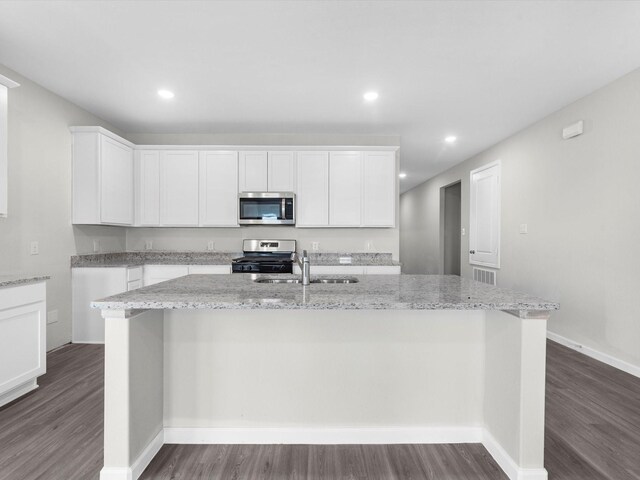 kitchen featuring sink, dark wood-type flooring, appliances with stainless steel finishes, a center island with sink, and white cabinets