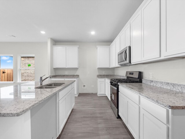 kitchen featuring light hardwood / wood-style flooring, stainless steel appliances, sink, a center island with sink, and white cabinets