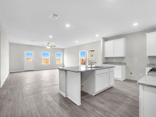 kitchen with a center island with sink, ceiling fan, light wood-type flooring, and white cabinetry