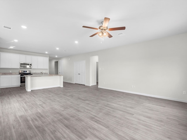 unfurnished living room featuring ceiling fan, light hardwood / wood-style floors, and sink