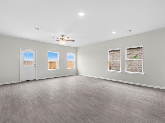 empty room with ceiling fan, a wealth of natural light, and light hardwood / wood-style floors