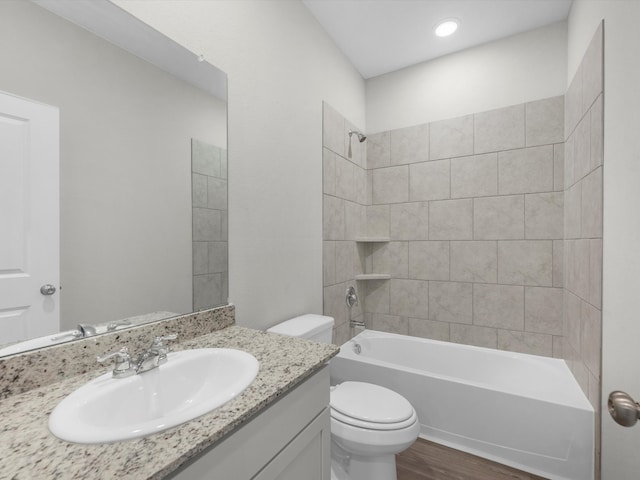 full bathroom with wood-type flooring, toilet, tiled shower / bath combo, and vanity