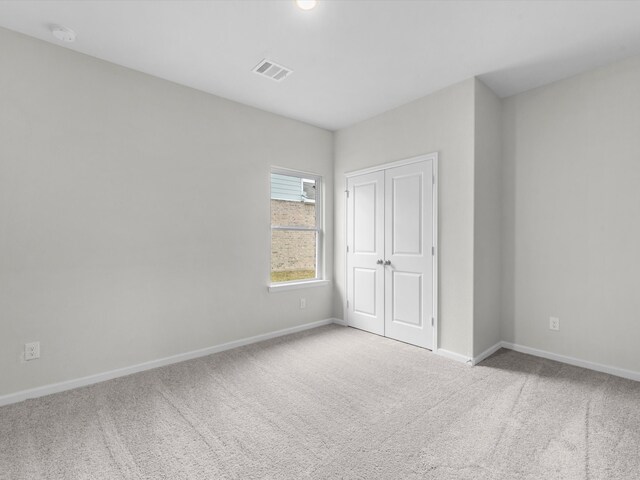 unfurnished bedroom with a closet and light colored carpet