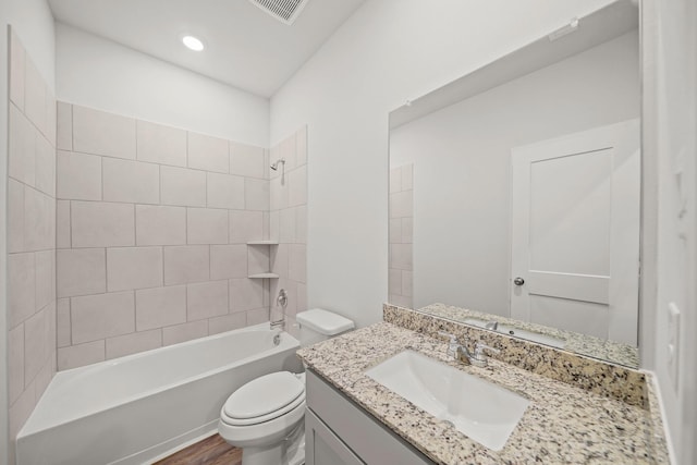 full bathroom with vanity, hardwood / wood-style flooring, toilet, and tiled shower / bath