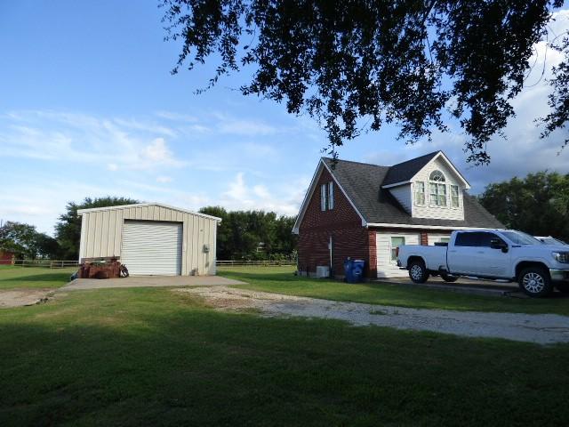 view of home's exterior with a garage, dirt driveway, a lawn, and an outdoor structure