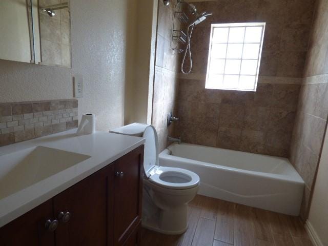 bathroom featuring a textured wall, toilet, wood finished floors, bathtub / shower combination, and vanity