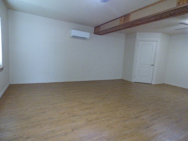 unfurnished room featuring a wall unit AC and light hardwood / wood-style floors