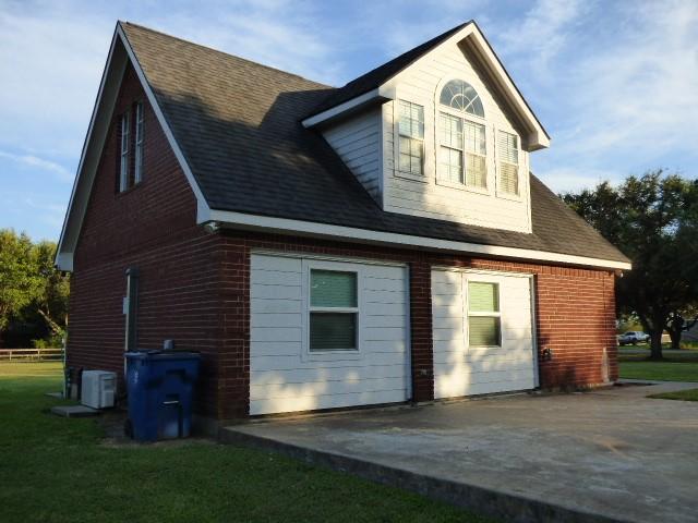 rear view of property featuring a shingled roof, a patio area, and a yard