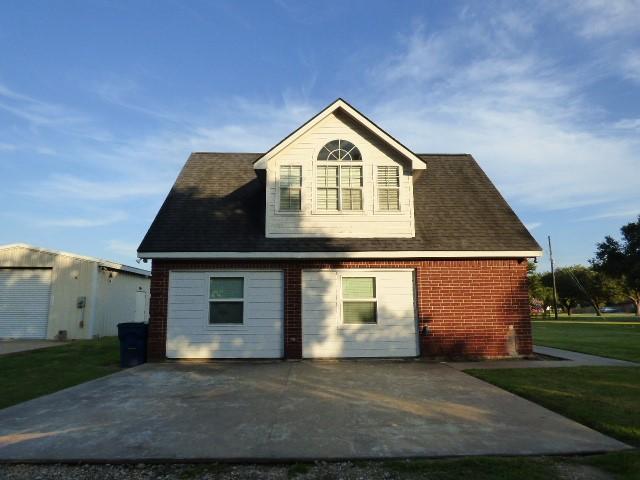 back of property with brick siding and a lawn