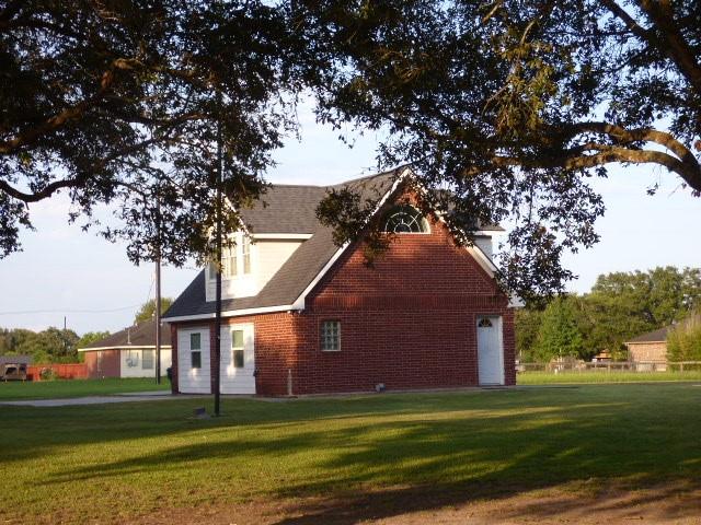 view of home's exterior with brick siding and a lawn