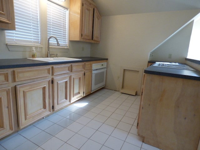 kitchen featuring light tile patterned flooring, light brown cabinets, sink, and oven