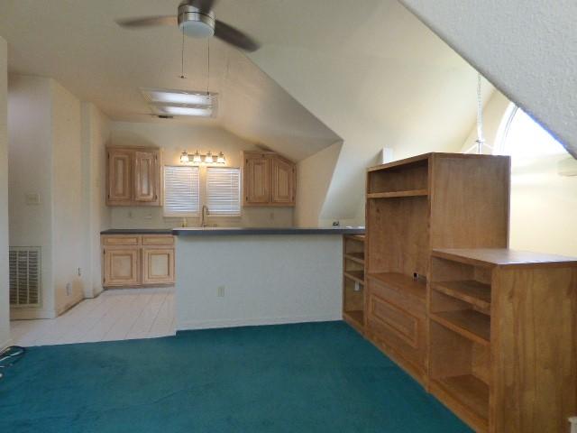 kitchen featuring light colored carpet, lofted ceiling, visible vents, and open shelves