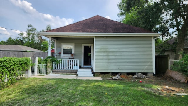 rear view of house with a porch and a lawn