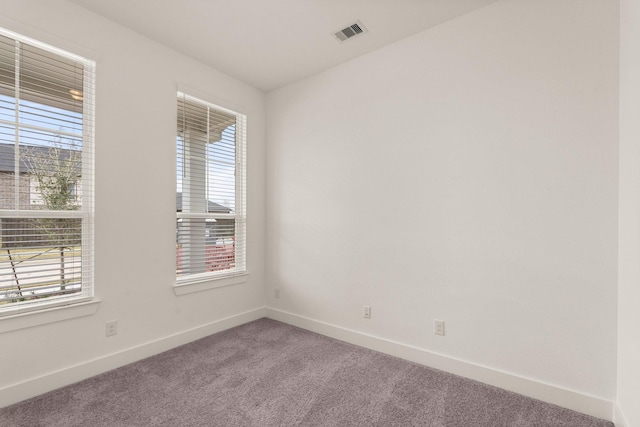 carpeted empty room with a wealth of natural light, visible vents, and baseboards