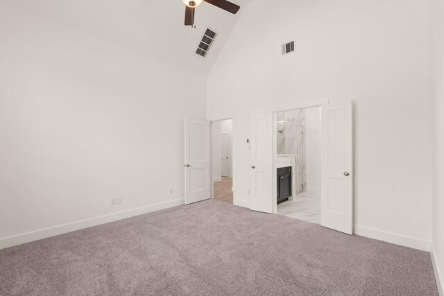 unfurnished bedroom featuring light carpet, high vaulted ceiling, visible vents, and ensuite bathroom