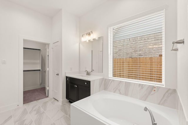 bathroom with a garden tub, a spacious closet, and vanity