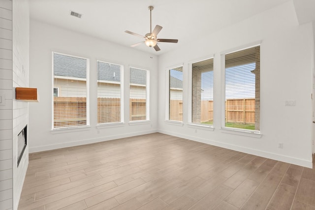 unfurnished sunroom with a large fireplace, ceiling fan, and visible vents