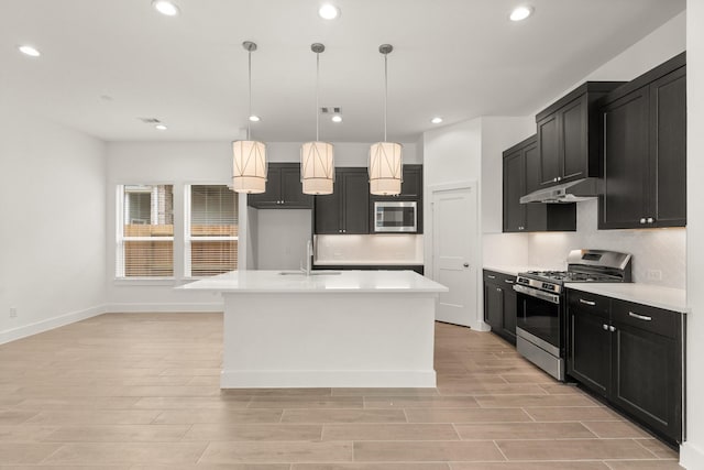 kitchen with pendant lighting, a center island with sink, stainless steel appliances, light countertops, and a sink